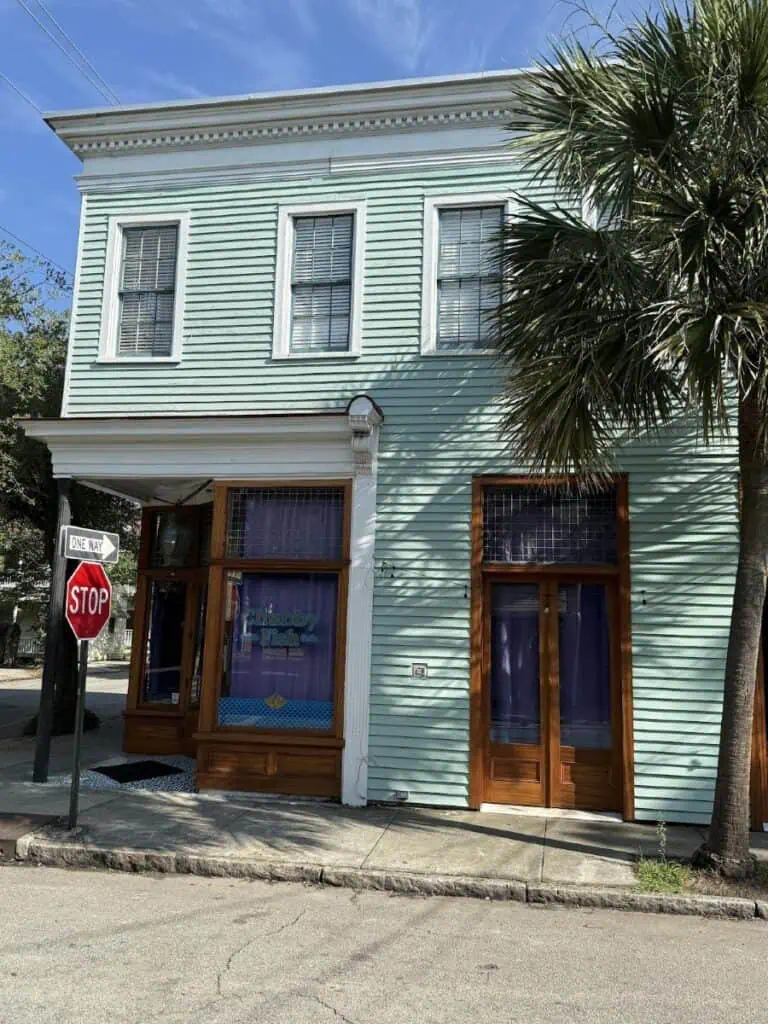 Light blue building with stop sign, palm tree nearby.