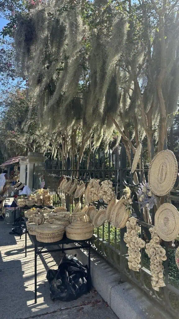 Woven baskets displayed under trees in outdoor market.