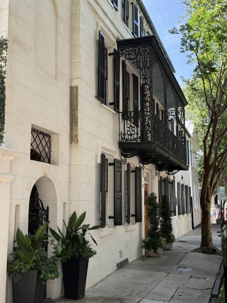 Historic building with wrought iron balcony and trees.
