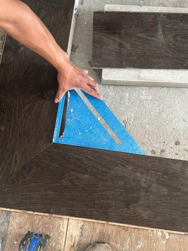 Person measuring wood floor with square tool