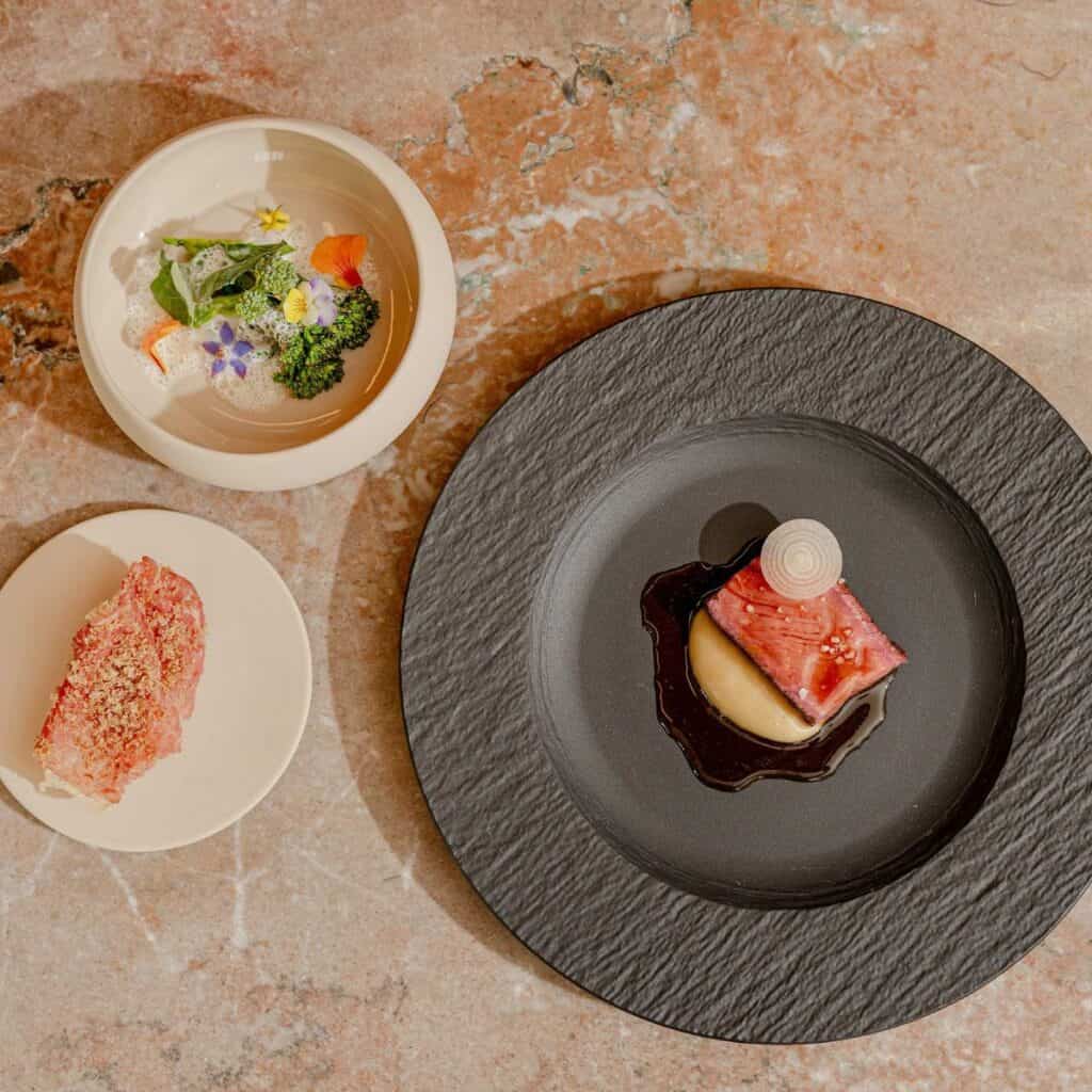 Gourmet dishes with meat, vegetables, and bread.