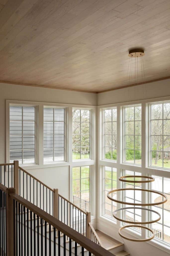 Modern staircase with large windows and circular chandelier.