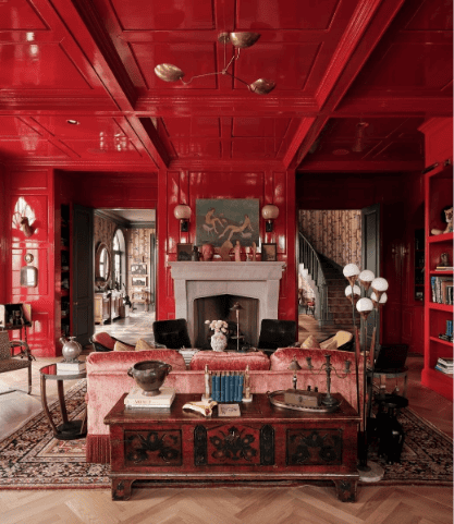 Luxurious red living room with fireplace and shelves.