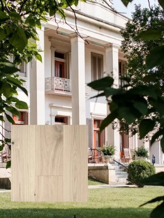 Wooden panel on lawn before columned building