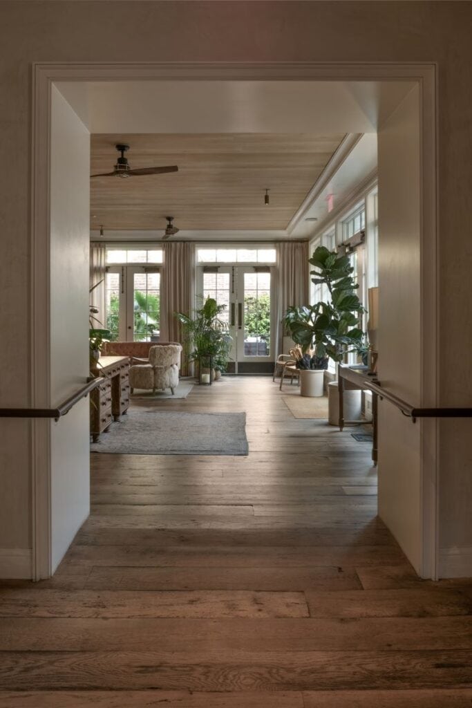 Warm wooden hallway leading to sunlit lounge